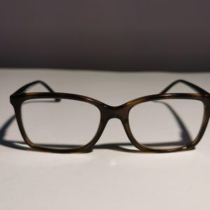 Op de afbeelding: Een bril met een bruin schildpad montuur, een vierkant frame en heldere glazen.