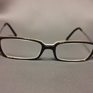 May include: Black rectangular eyeglasses with a thin white rim around the lenses.