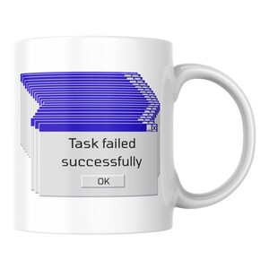 May include: A white ceramic mug featuring a repeating graphic of a blue and grey computer error window. The text on the window reads Task failed successfully with an OK button below. The design mimics a classic operating system interface.