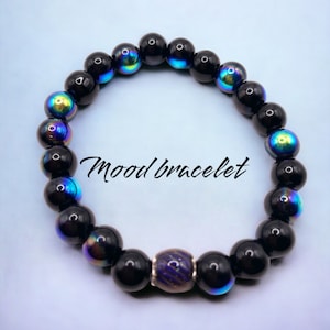 May include: A black mood bracelet with iridescent beads and a silver bead with a purple and blue swirl design. "Mood bracelet" is written in white text on a white background.