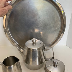 May include: A silver tea set with a teapot, creamer, and sugar bowl. The set is on a large silver tray.