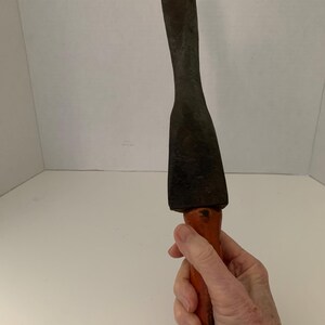 May include: A vintage wooden-handled metal chisel with a flat blade. The chisel is rusty and has a worn wooden handle.