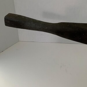May include: A close-up of the handle of a black metal tool. The handle is smooth and has a slightly rounded shape.