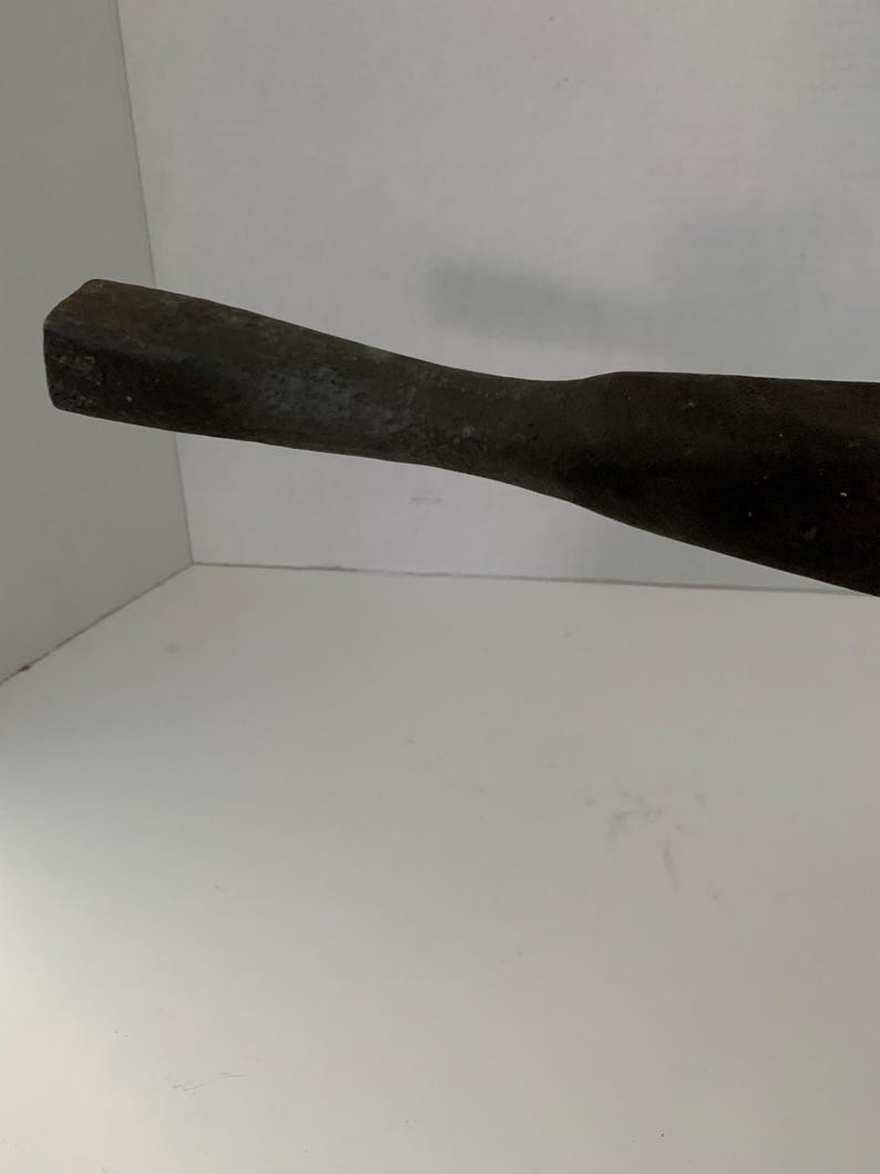 May include: A close-up of the handle of a black metal tool. The handle is smooth and has a slightly rounded shape.