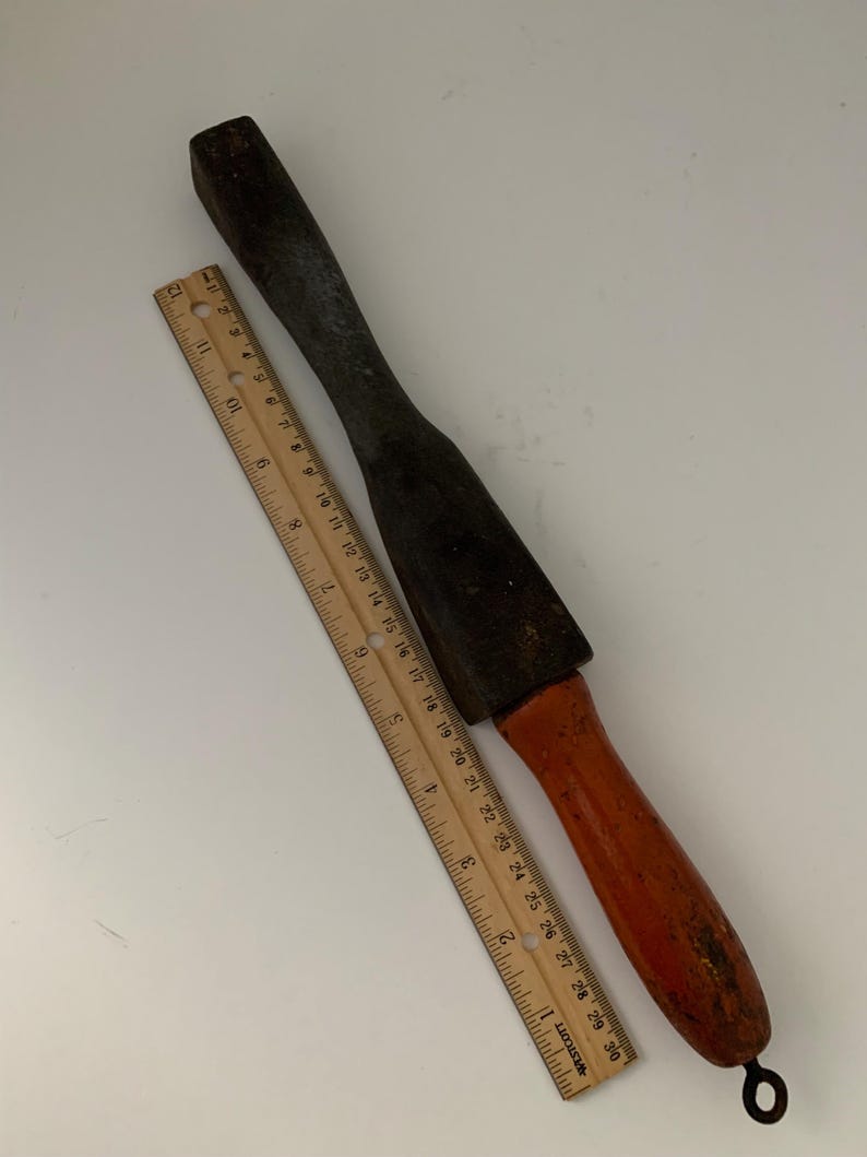 May include: A wooden and metal tool with a long, rectangular handle and a flat, rectangular head. The handle is painted orange and the head is black. The tool is about 12 inches long.