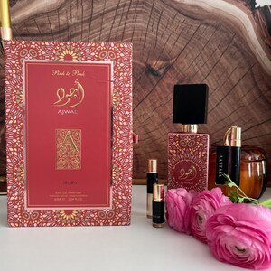 K&ouml;nnte beinhalten: Ein Parf&uuml;mset mit einer roten Schachtel und Flasche, goldenen Details und dem Text "AJWAL" und "Lattafa". Das Set enth&auml;lt kleine Fl&auml;schchen und rosa Blumen. Auf der Schachtel steht "Pink to Pink" und "EAU DE PARFUM 60ml".