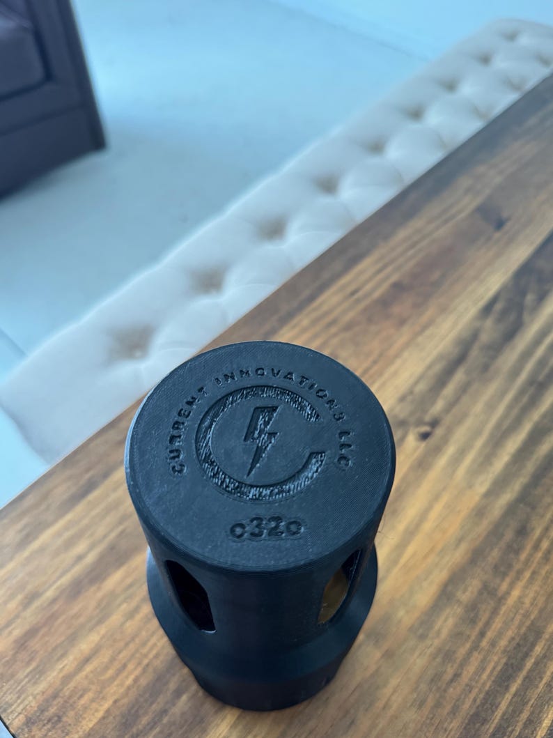 May include: Black plastic electrical outlet cover with the text "Current Innovations LLC" and a lightning bolt logo. The cover has a number "0320" printed on it.