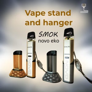 Peut inclure: Image d'un support et d'un support pour vape. L'image montre un stylo vape dor&eacute; et argent&eacute; avec un embout buccal noir et deux supports. Un support est dor&eacute; avec un motif g&eacute;om&eacute;trique, et l'autre est gris avec un motif similaire. Le texte "SMOK novo eko" est visible.