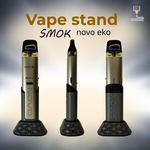Peut inclure: Un support de vape avec le texte "Vape stand" et "SMOK novo eko". Le support est con&ccedil;u pour contenir trois stylos vape. Les stylos vape sont argent&eacute;s et noirs. Le support est gris avec un motif g&eacute;om&eacute;trique.