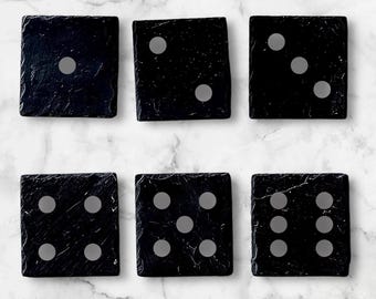 May include: Six black slate dice with white dots. The dice are arranged in two rows of three. The dice show the numbers one, two, three, four, five, and six.
