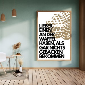 May include: A white poster with a black and white graphic of a waffle. The text on the poster reads "Lieber einen an der Waffel haben, als gar nichts gebacken bekommen."