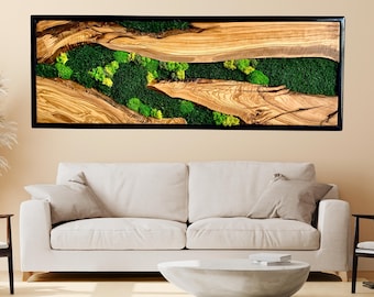 May include: A rectangular wall art piece featuring a natural wood design with a black frame. The artwork incorporates green moss and lighter green accents, creating a nature-inspired aesthetic. The wood grain is visible, adding texture.