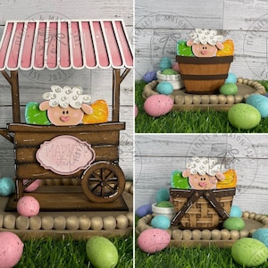 May include: A wooden market stand with a pink striped awning, featuring a white sheep with brown eyes and a pink nose. The stand is decorated with colourful Easter eggs and a sign that reads "Market Stand".