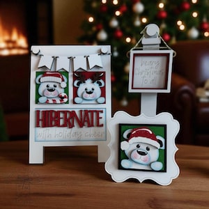 May include: White wooden Christmas decor featuring polar bear faces wearing Santa hats and reindeer antlers. The sign reads "HIBERNATE with holiday cheer" and "beary Christmas to all". Festive holiday decorations.