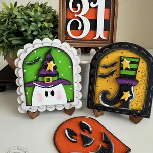 May include: A collection of Halloween-themed wooden decorations. Includes a '31' sign, a ghost in a witch hat, a witch's boot, and a jack-o'-lantern face. Each piece has a unique design with orange, black, green, and white colors, perfect for seasonal decor.