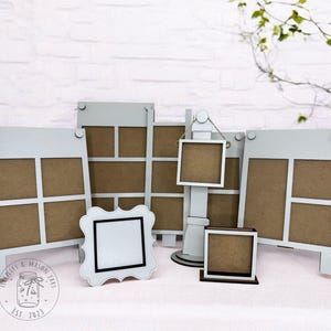 May include: A collection of white wooden photo frames in various sizes and styles. The frames include multi-photo displays, a stand-up frame, and a decorative scalloped-edge frame. The frames have a neutral color palette, with brown backing and are arranged on a light surface.