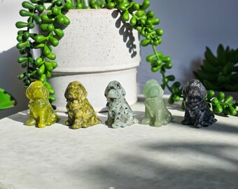 May include: Five small carved stone dog figurines. The dogs are sitting and facing forward. The dogs are carved from green, black, and white stone.