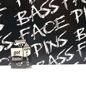 May include: Black and white enamel pin of a milk carton with the text "got Riddim?" and "100% Filthy" on it.