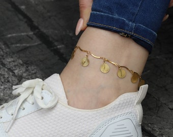 May include: Gold anklet with a delicate chain and multiple small, round, sun-shaped charms.
