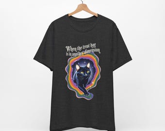Puede incluir: Una camiseta gris oscuro con un gato negro caminando a través de un portal arcoíris. El texto "When the treat bag is in another dimension" está impreso en la camiseta.