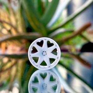 May include: A white wheel with a heart-shaped design. The wheel is made of plastic and has a smooth finish.