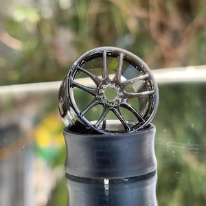 May include: A black rim with a 5-spoke design, the rim is sitting on a black tire.