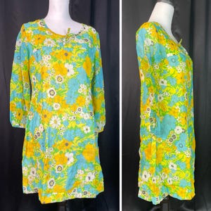 May include: A vintage 1960s style dress with a floral print in shades of yellow, blue, and green. The dress has a scoop neck and three-quarter sleeves.