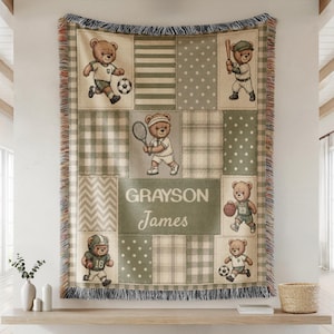 May include: A woven throw blanket featuring a patchwork design in sage green, cream, and brown. The blanket displays teddy bears playing various sports including soccer, baseball, tennis, and basketball. The name Grayson James is printed in the center.