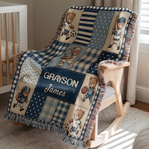 Könnte beinhalten: Eine gewebte Wohndecke mit Patchwork-Design in Blau-, Creme- und Weißtönen. Die Decke zeigt Illustrationen von Teddybären, die verschiedene Sportarten wie Fußball, Baseball und Basketball ausüben, mit dem aufgedruckten Namen GRAYSON James.