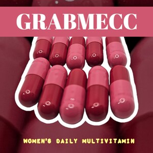 Op de afbeelding: Een close-up van tien roze en rode capsules gerangschikt in twee rijen. De capsules liggen in een witte tray met de tekst "GRABMECC" en "WOMEN'S DAILY MULTIVITAMIN" in de afbeelding.