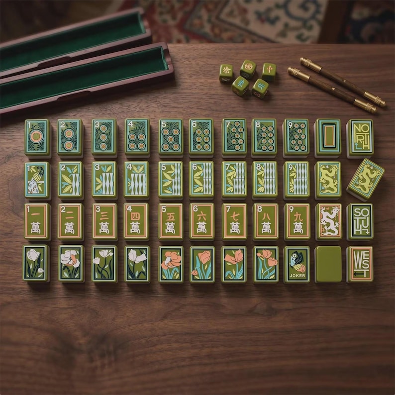 May include: A set of rectangular mahjong tiles with green, tan, and white floral, numerical, and dragon designs. The set includes two wooden storage cases, two brown metal sticks, and five small green dice arranged on a dark wooden surface.