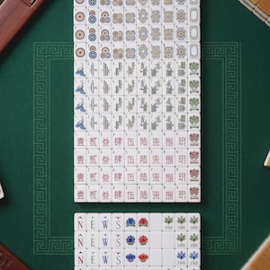 Pode incluir: Um conjunto de pe&ccedil;as brancas de Mahjong dispostas numa grelha, com v&aacute;rios naipes incluindo c&iacute;rculos, bambu e caracteres chineses. As pe&ccedil;as exibem os n&uacute;meros de um a nove, as letras direcionais N, E, W, S, padr&otilde;es florais e etiquetas Joker.