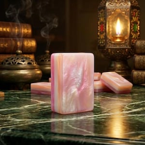 Puede incluir: Un bloque rectangular con un acabado jaspeado en rosa y blanco nacarado se mantiene en posici&oacute;n vertical. La superficie tiene una textura lisa y brillante con sutiles remolinos de color en todo el material, creando un aspecto reflectante en la cara frontal.