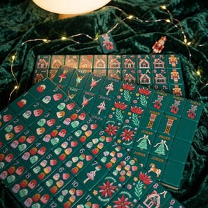 May include: A set of dark green mahjong tiles featuring festive holiday illustrations including gingerbread houses, nutcrackers, ballet dancers, poinsettias, Christmas trees, and colorful sweets. Each tile displays clear numbers or text labels.