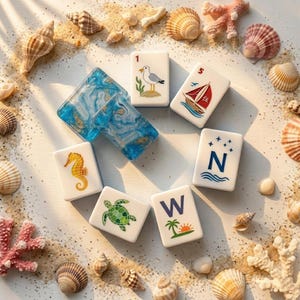 May include: A collection of rectangular mahjong tiles featuring nautical illustrations including a seagull, a sailboat, a seahorse, a sea turtle, and the letters N and W with a palm tree, alongside two blue marbled resin tiles and various seashells.