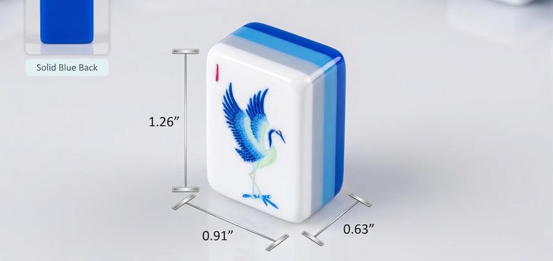 Op de afbeelding: Een rechthoekige mahjongtegel met een blauwe kraanvogelillustratie op een witte voorzijde en een effen blauwe achterzijde. De tegel is 3,2 cm hoog, 2,31 cm breed en 1,6 cm diep, met een kleine rode markering in de linkerbovenhoek.