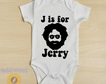 Pode incluir: Body de bebé branco com um gráfico preto de um rosto barbudo usando óculos de sol, com o texto "J is for Jerry". O body de manga curta tem fechos de pressão. O design está centrado na frente.