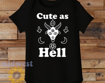 May include: Black baby onesie with white text that reads "Cute as Hell" and a white illustration of a goat with horns, a pentagram, and a flame above its head.