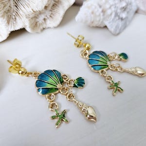 May include: Gold tone dangle earrings with a blue and green seashell charm, starfish, and seashell charms hanging from it.