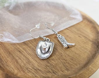 May include: A pair of silver earrings with a cowboy hat and a cowboy boot charm.