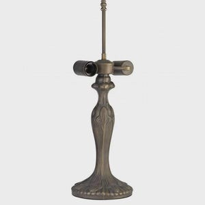 May include: A bronze-colored lamp base with a decorative, Art Nouveau-inspired design. The base features a detailed, textured pattern and a slender, elongated stem. The lamp has two bulb sockets and a central rod topped with a decorative finial.