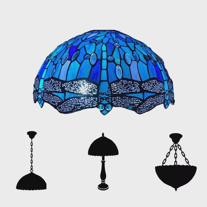 May include: A blue stained glass lampshade with a dragonfly design. The lampshade is dome-shaped and features various shades of blue glass. Silhouettes of different lamp styles are below the lampshade.