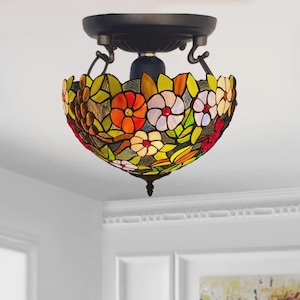 May include: A stained-glass ceiling light with a floral pattern. The light fitting has a dark bronze base and a bowl-shaped shade with red, orange, yellow, and white flowers. The shade is approximately 30 cm in diameter.
