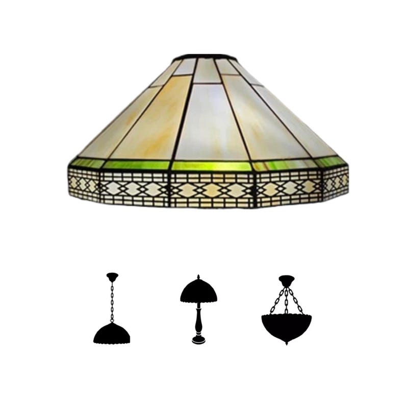 May include: A stained glass lampshade with a geometric design. The shade features a cream and yellow color scheme with black lines and a green border. Below the lampshade are three black silhouette illustrations of different lamp styles.
