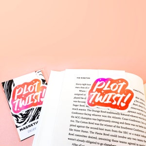 Peut inclure: Deux autocollants aquarelle rose et orange avec le texte "PLOT TWIST!" en blanc. Les autocollants sont sur un fond blanc.