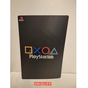 May include: Black PlayStation game case with the PlayStation logo and the four button symbols: square, cross, circle, and triangle.
