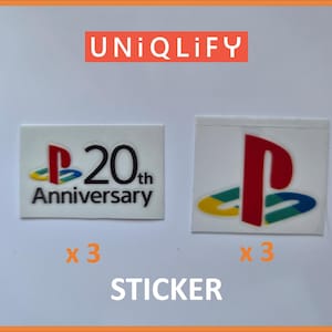 Peut inclure: Deux autocollants rectangulaires présentant le logo PlayStation. L'autocollant de gauche affiche le logo avec le texte 20th Anniversary. L'autocollant de droite montre le logo PlayStation classique multicolore. Les deux sont marqués x 3, avec UNIQLIFY et STICKER.