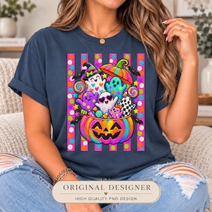 May include: A dark blue t-shirt featuring a vibrant graphic of a large, rainbow-colored jack-o'-lantern filled with various colorful ghosts, lollipops, and candy. The design is set against a background of vertical pink and orange polka-dot stripes.