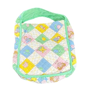 May include: A quilted shoulder bag with a repeating pattern of cartoon characters, balloons, and diamonds in pastel colors. The bag has a green strap and trim, and is likely vintage or retro.