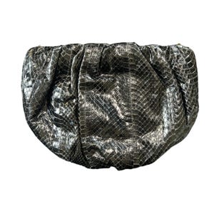 Puede incluir: Un clutch plateado y negro con un estampado de piel de serpiente. El bolso tiene un diseño fruncido y una forma redondeada. El material tiene un aspecto brillante y texturizado, que refleja la luz. El clutch es un accesorio de moda.